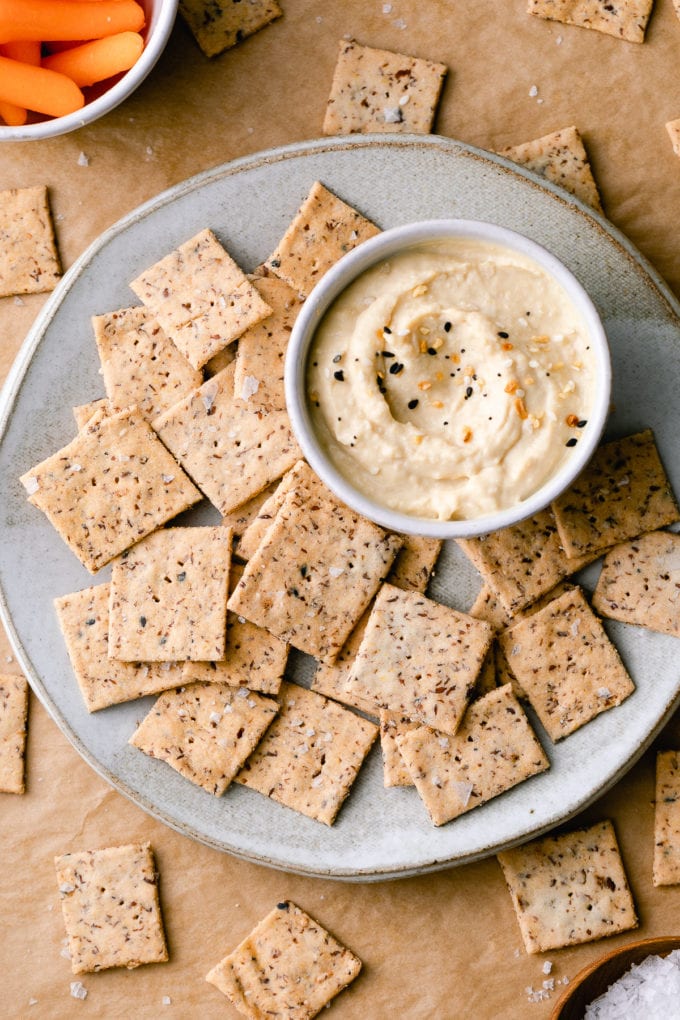 top down view of almond flour crackers with hummus on a plate.