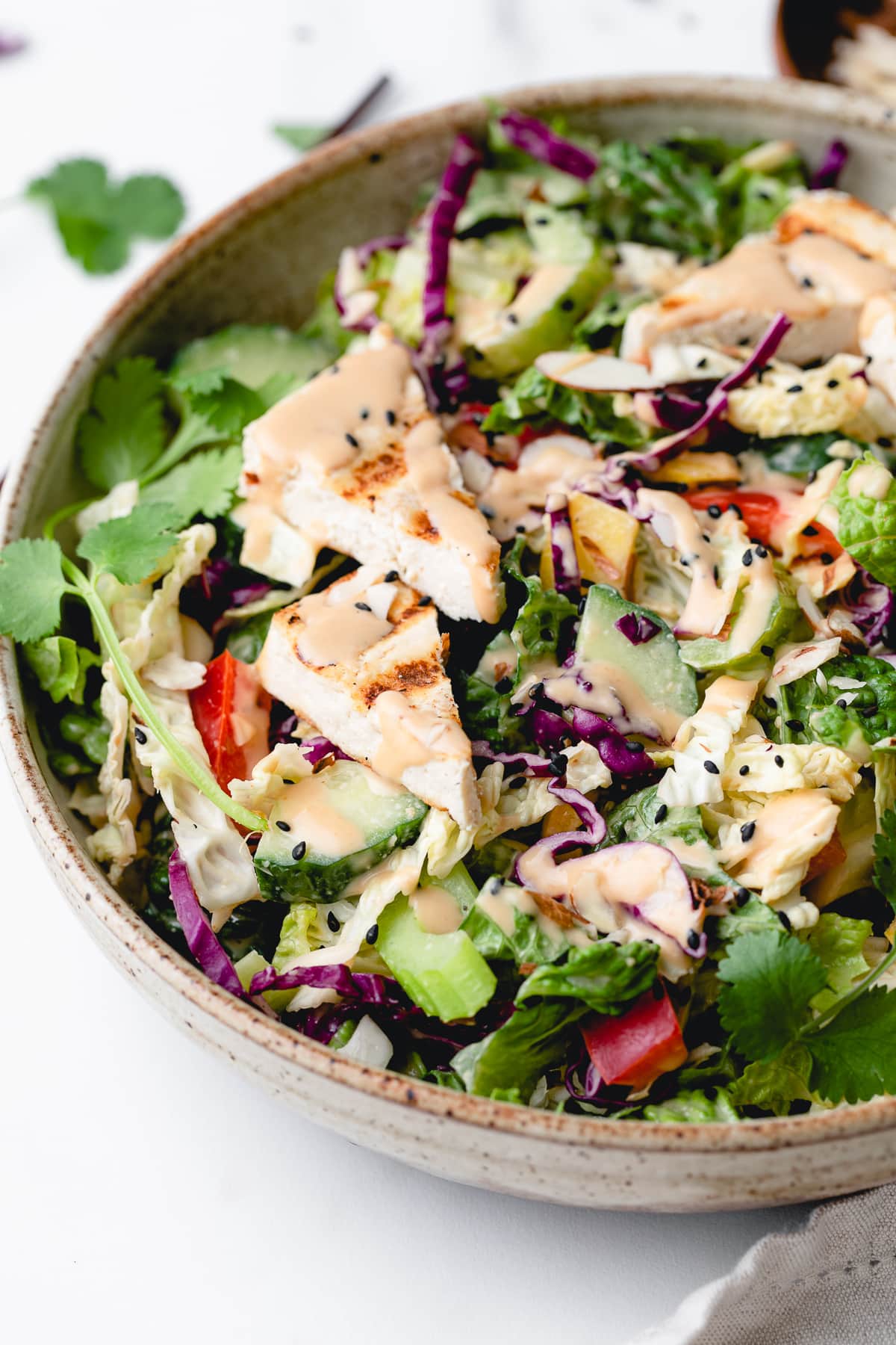 side angle view of Asian chopped salad in a bowl with items surrounding.