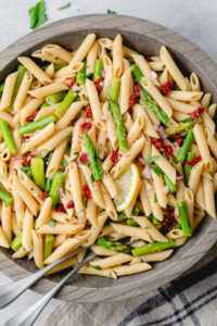 top down view of wooden bowl with garlic lemon asparagus pasta salad.