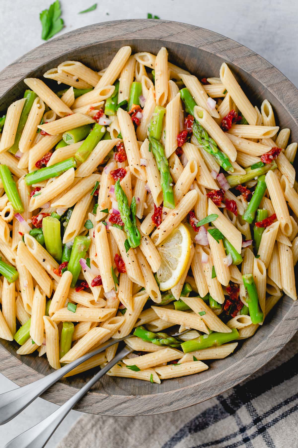 top down view of wooden bowl with garlic lemon asparagus pasta salad.