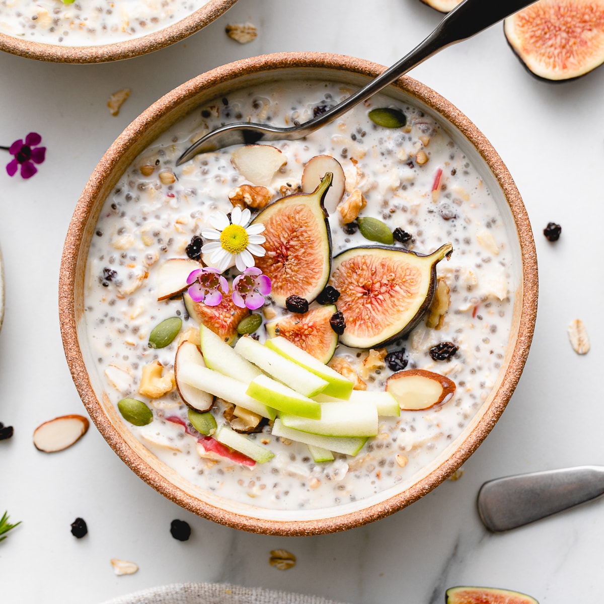 top down view of bowl of bircher muesli with fruits and nuts with items surrounding.