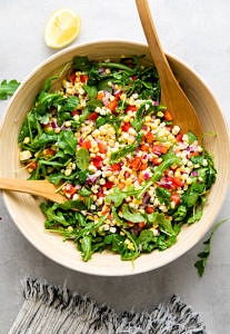 top down view of freshly tossed corn arugula salad.