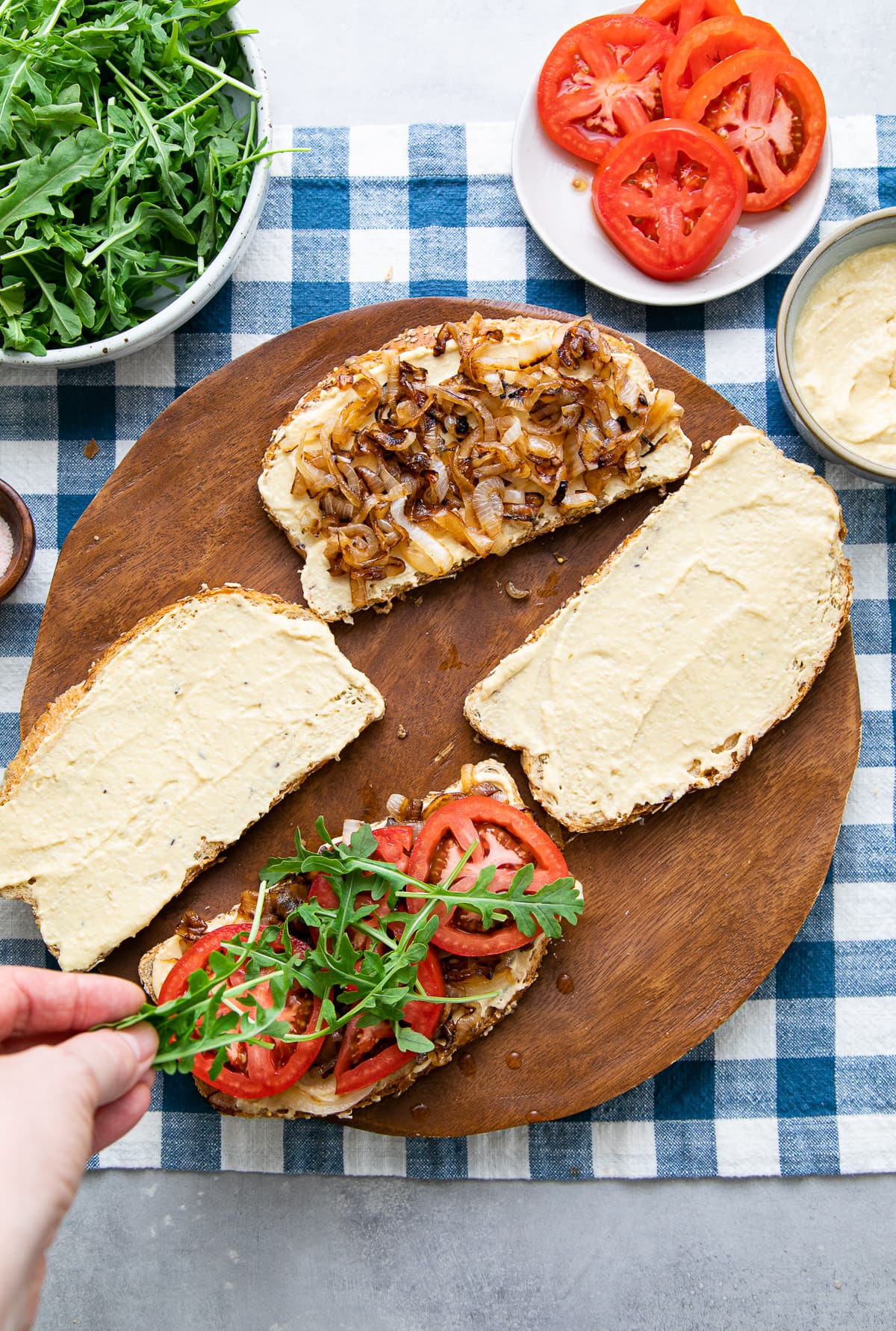 top down view showing the process of layering hummus sandwich halves