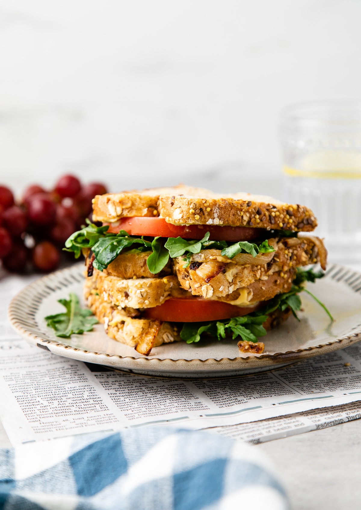 head on view of two halves of grilled hummus sandwich stacked on a small plate.