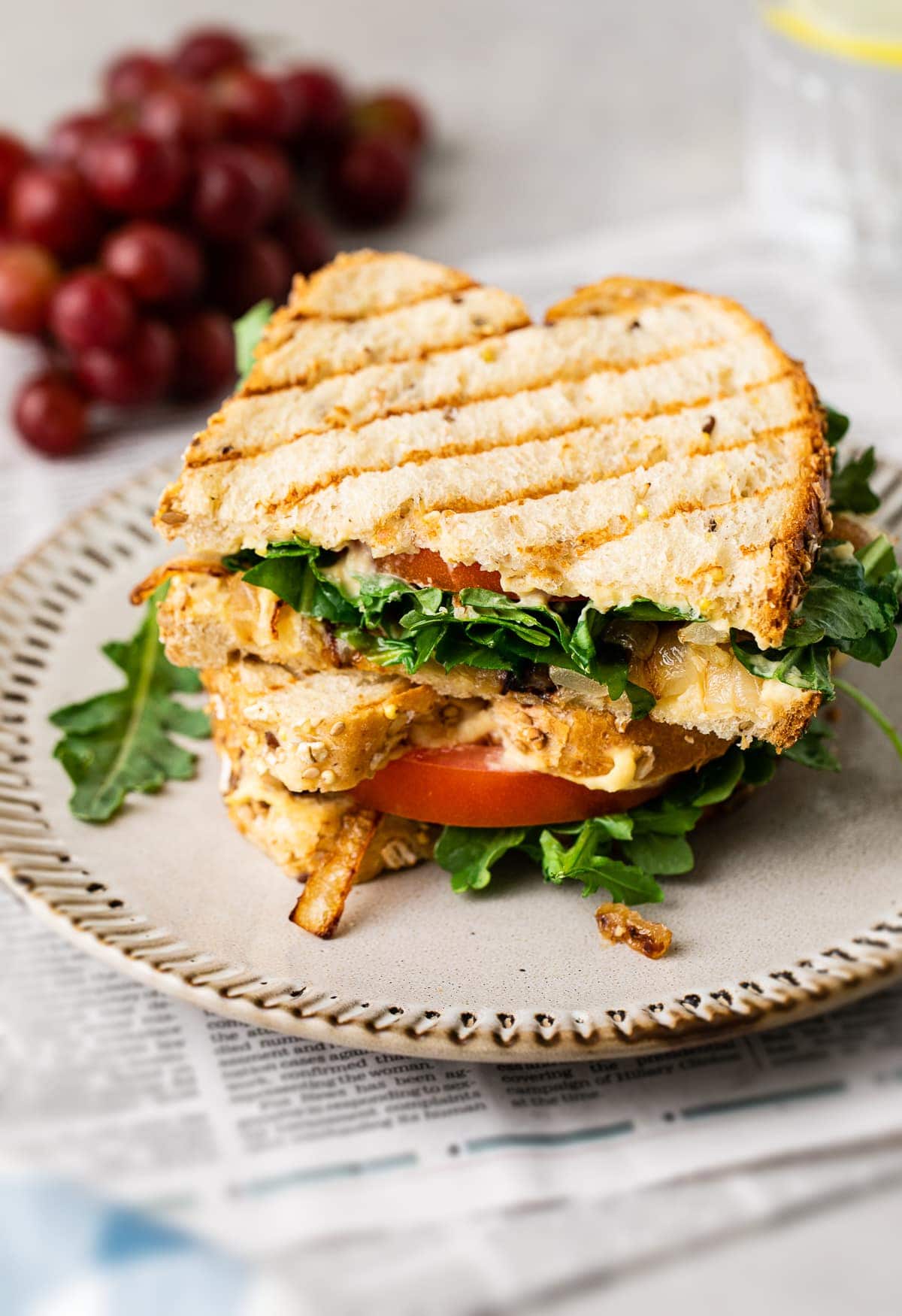 side angle view of two halves of grilled hummus sandwich stacked on a small plate.