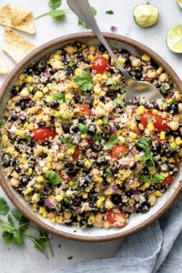 top down view of freshly made southwest quinoa salad in a serving bowl with spoon.