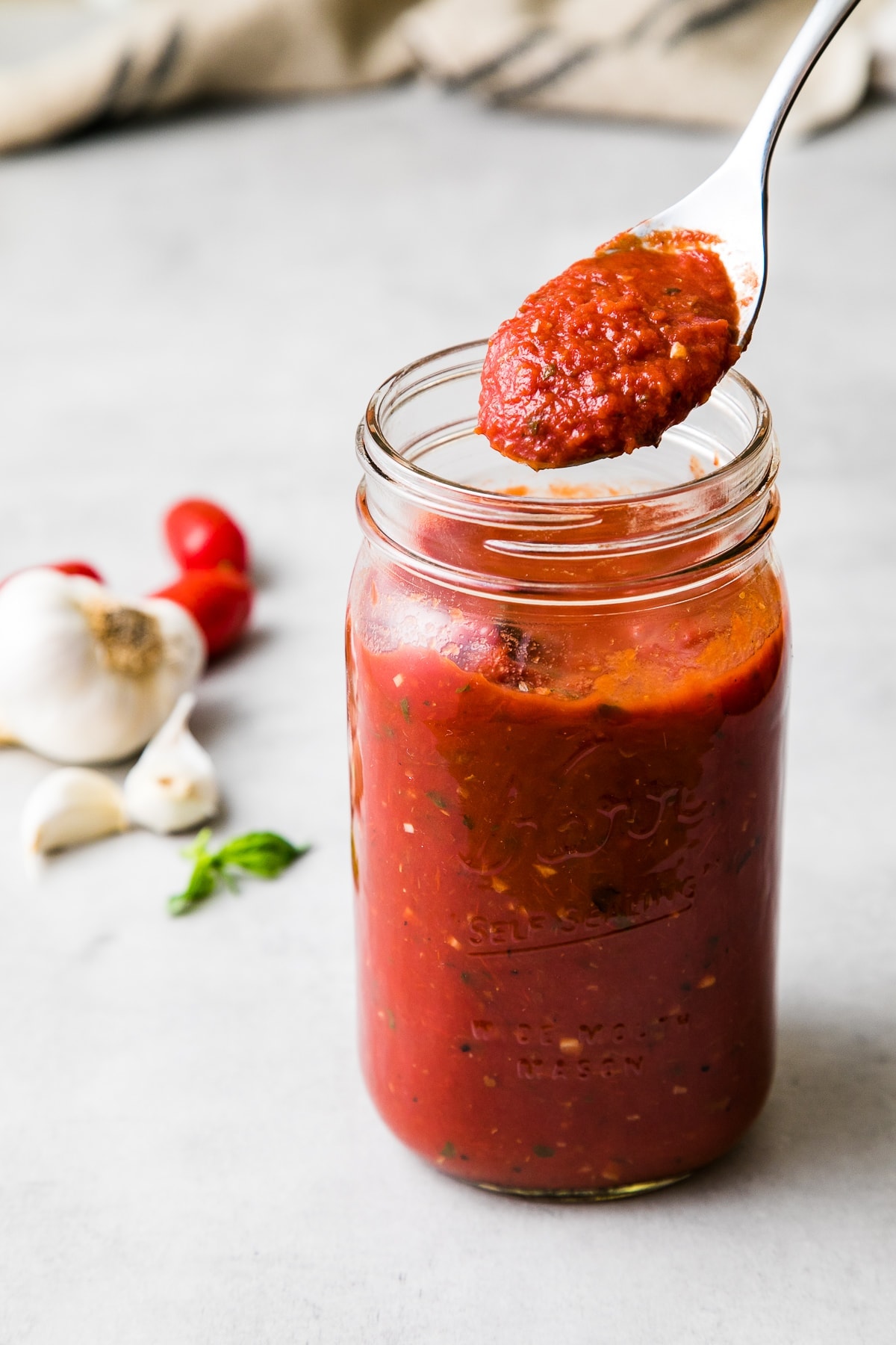 side angle view of jar of homemade marinara sauce with spoonful.