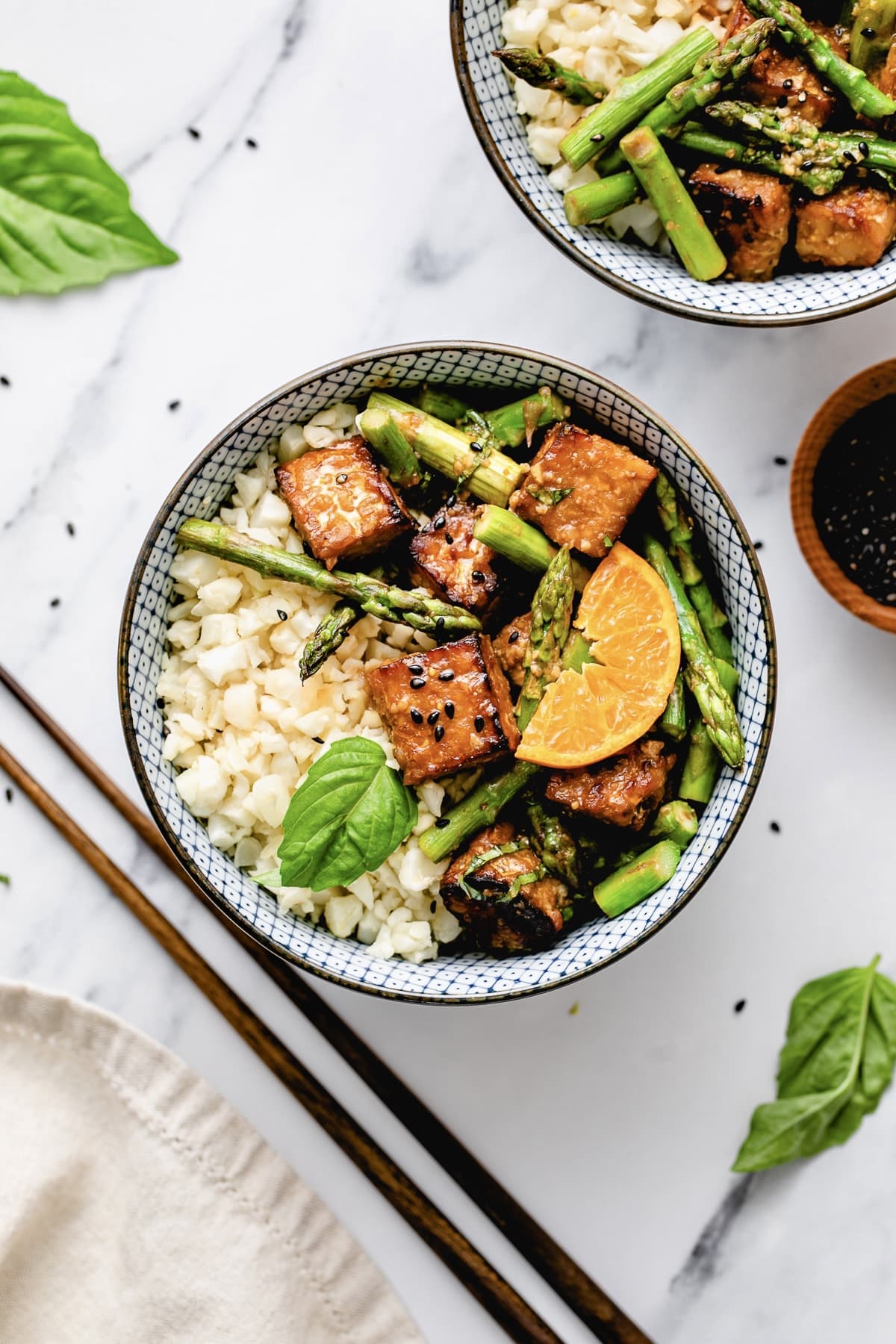 top down view of bowl of orange tempeh and asparagus with cauliflower rice.