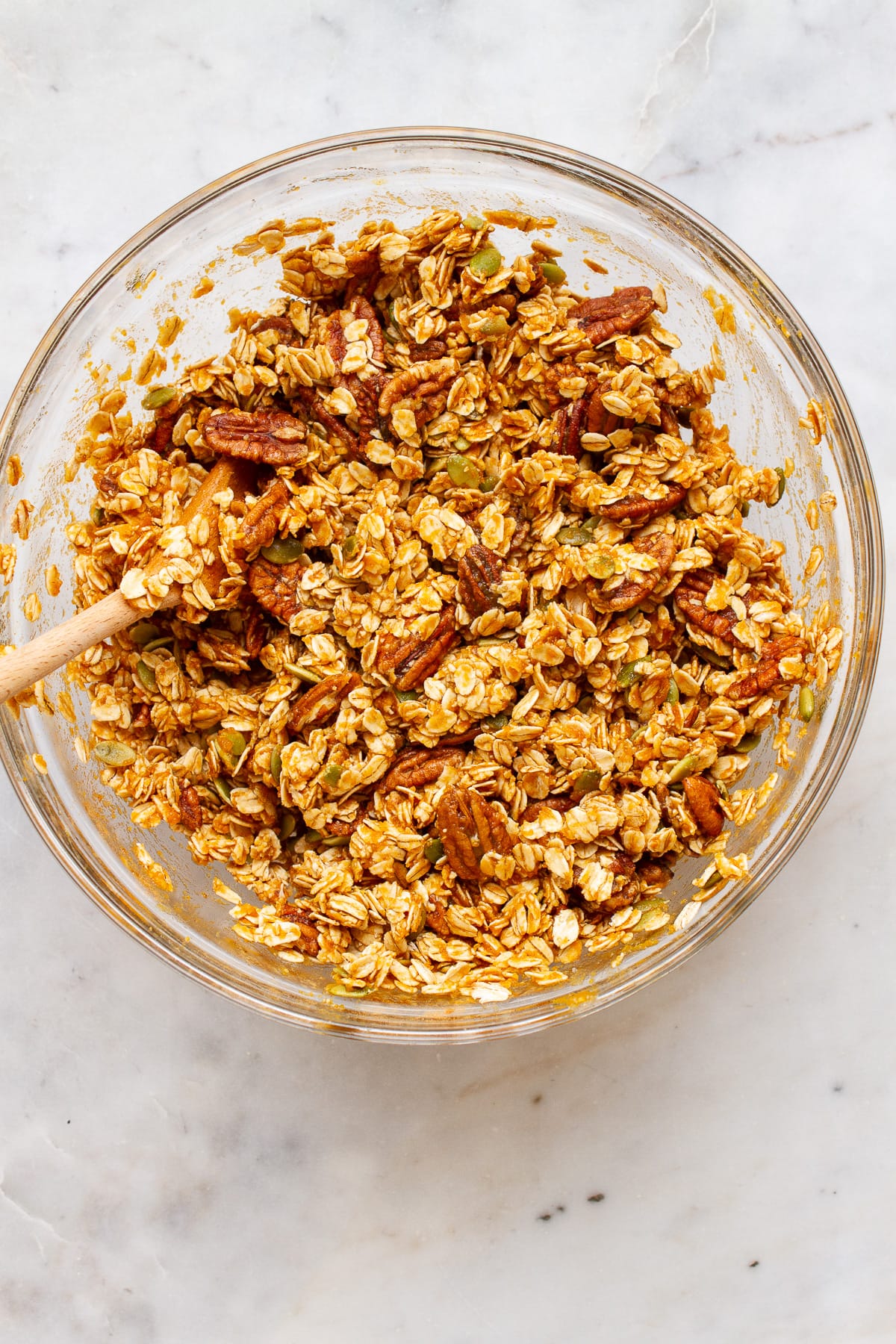 top down view of a bowl with all ingredients for pumpkin granola added and mixed.