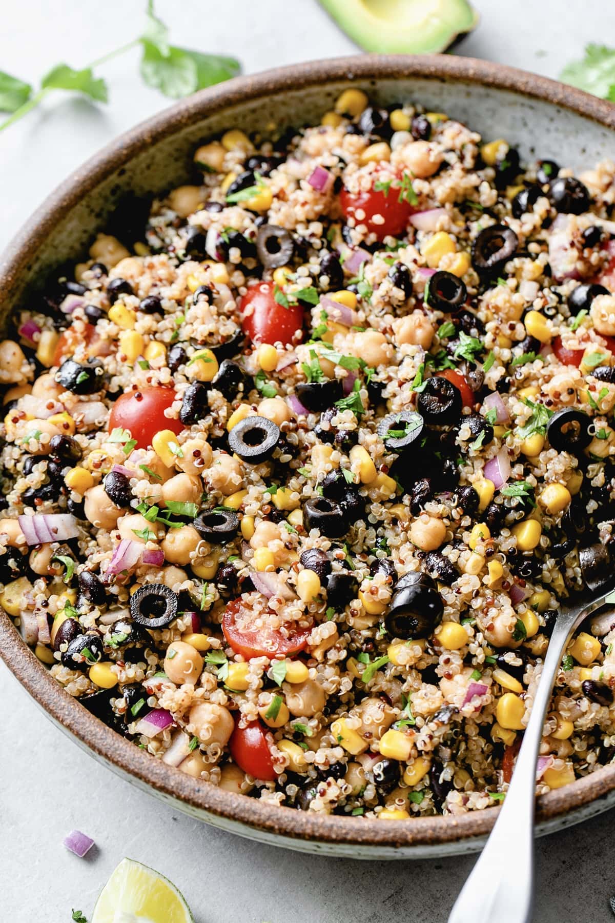 side angle view of freshly made southwest quinoa salad in a serving bowl with spoon.