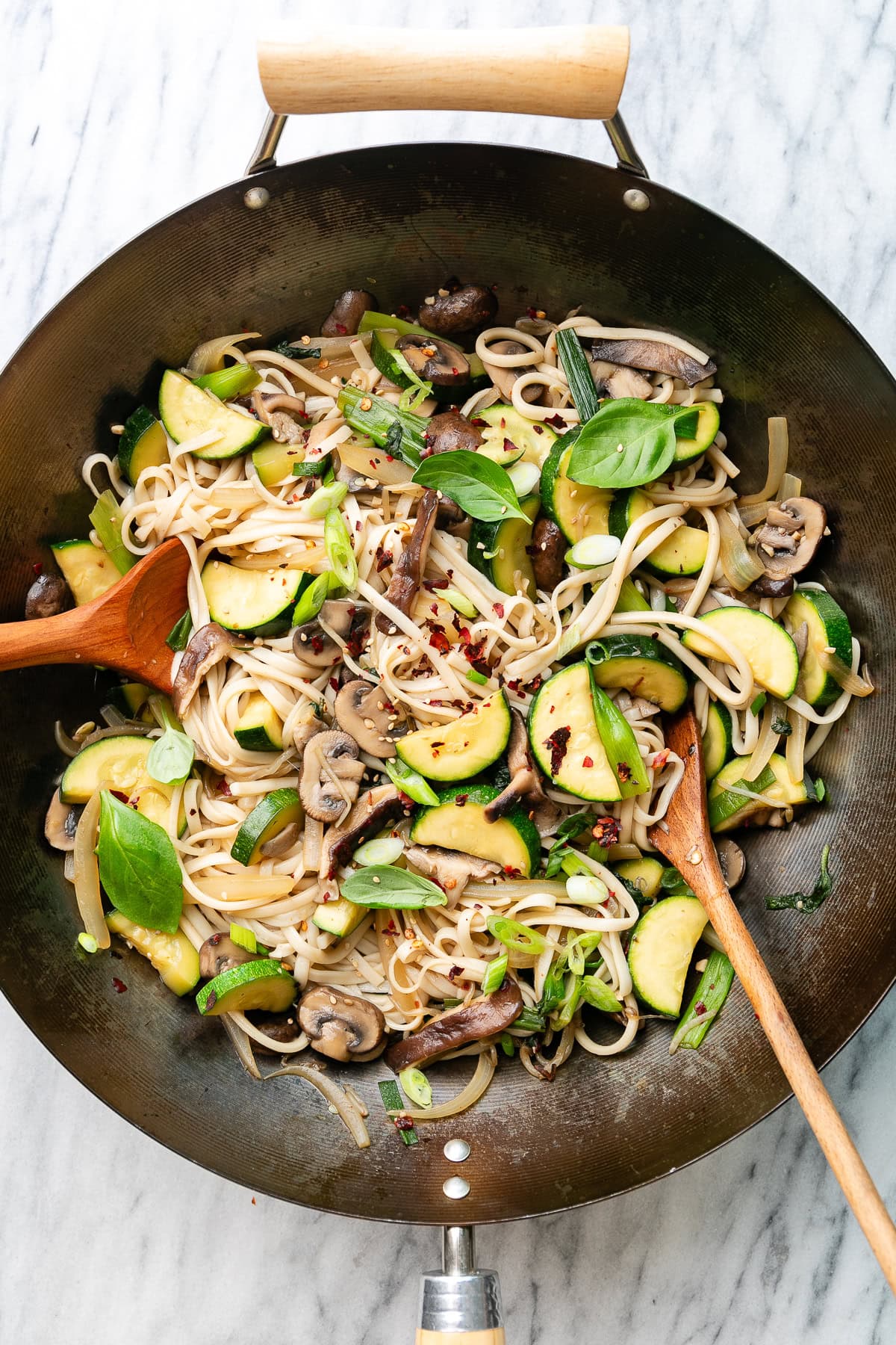 up close view of freshly stir-fried udon noodles with veggies in a wok.