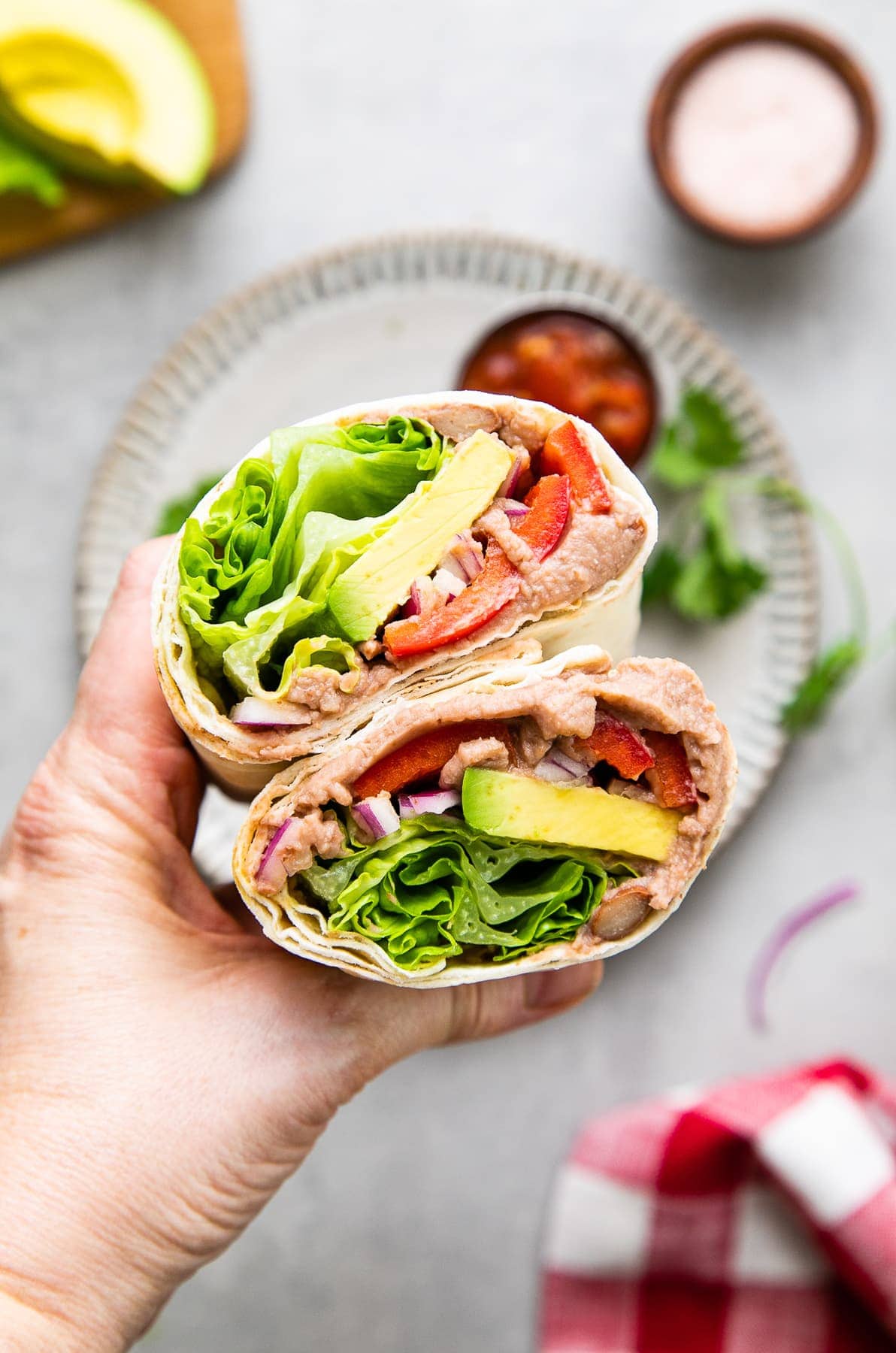 top down view of hand holding refried bean avocado lavash wrap sliced in half.