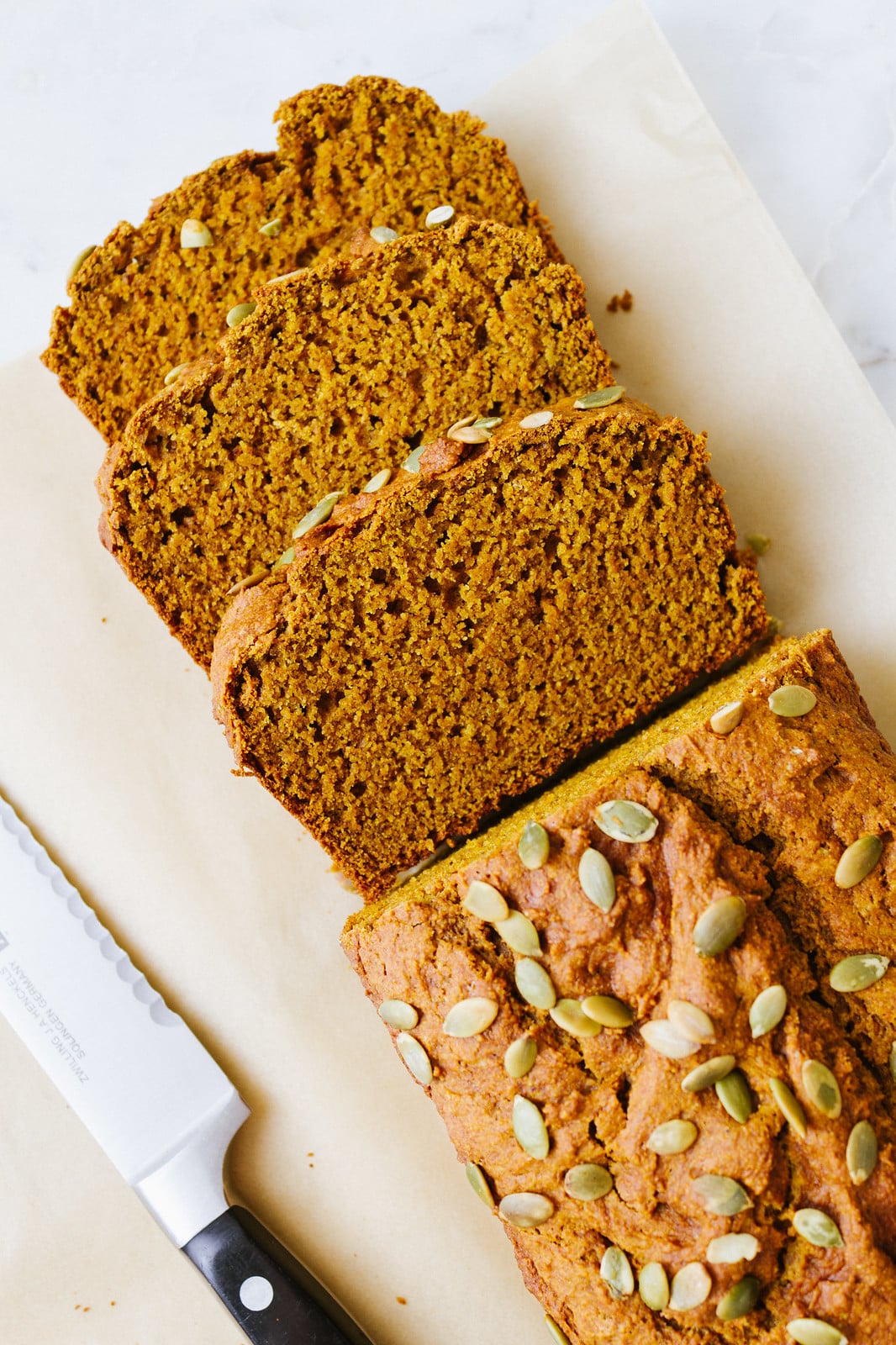 top down view of sliced vegan pumpkin bread on parchment paper.