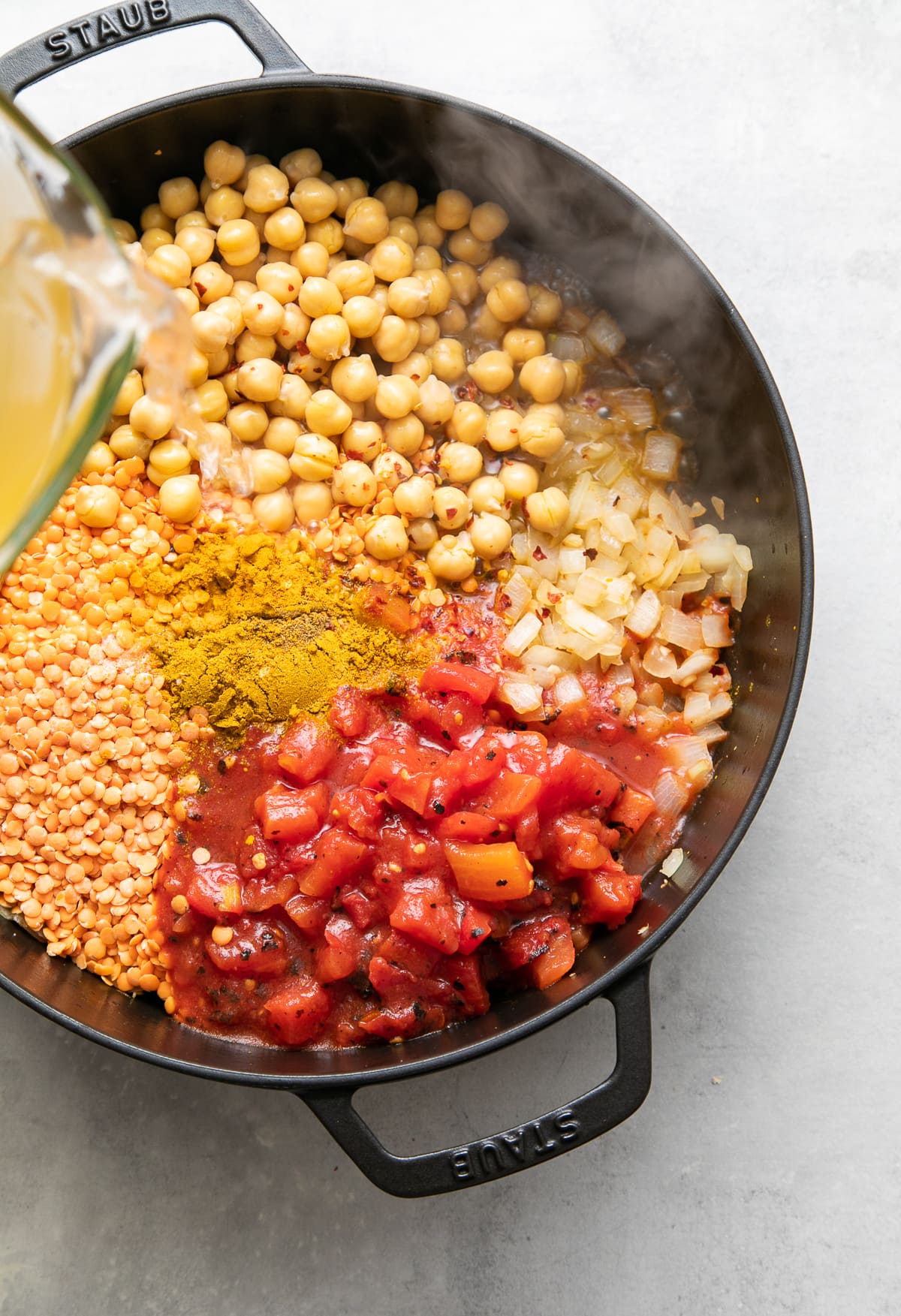 top down view showing the process of making curry red lentil stew with chickpeas and kale.