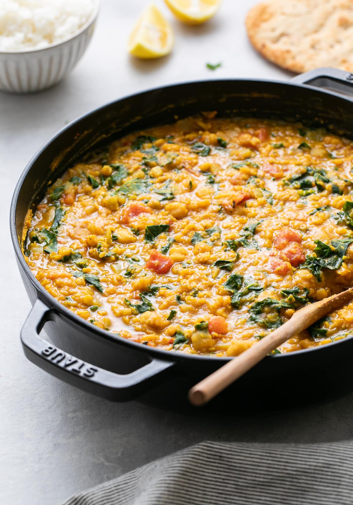 side angle view of curry red lentil stew in a pot with items surrounding.