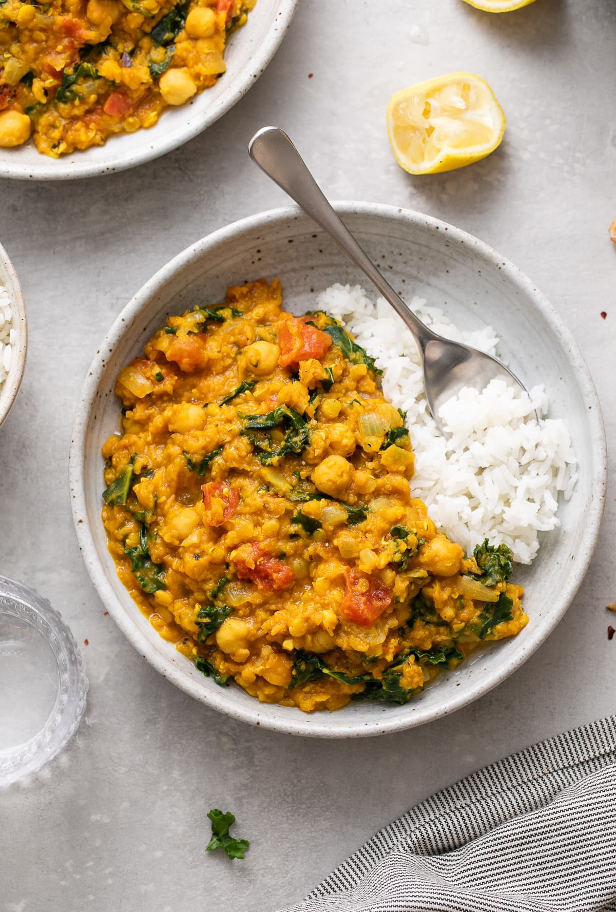 top down view of a bowl with a serving of curry red lentil stew with items surrounding.