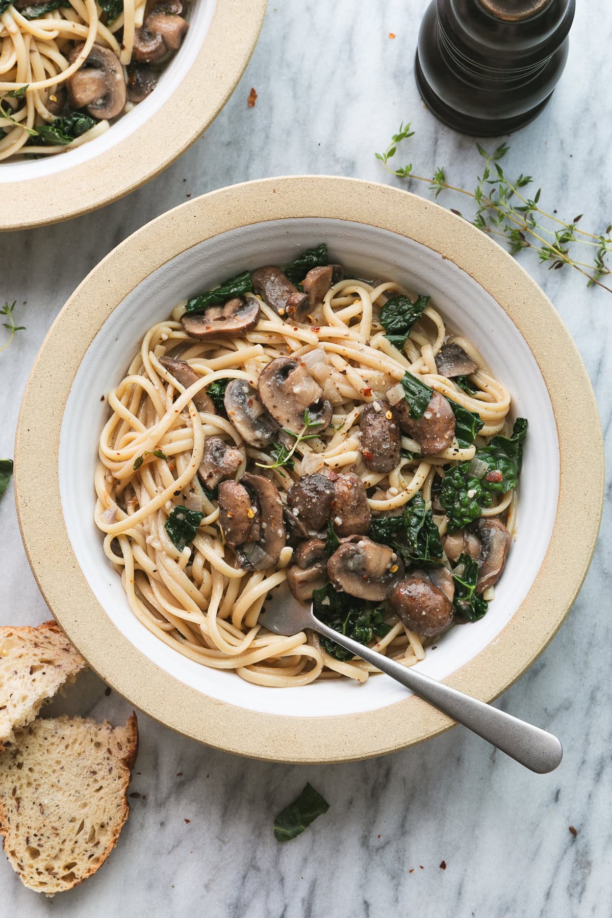 op down view of bowl with freshly made mushroom and kale pasta with items surrounding.