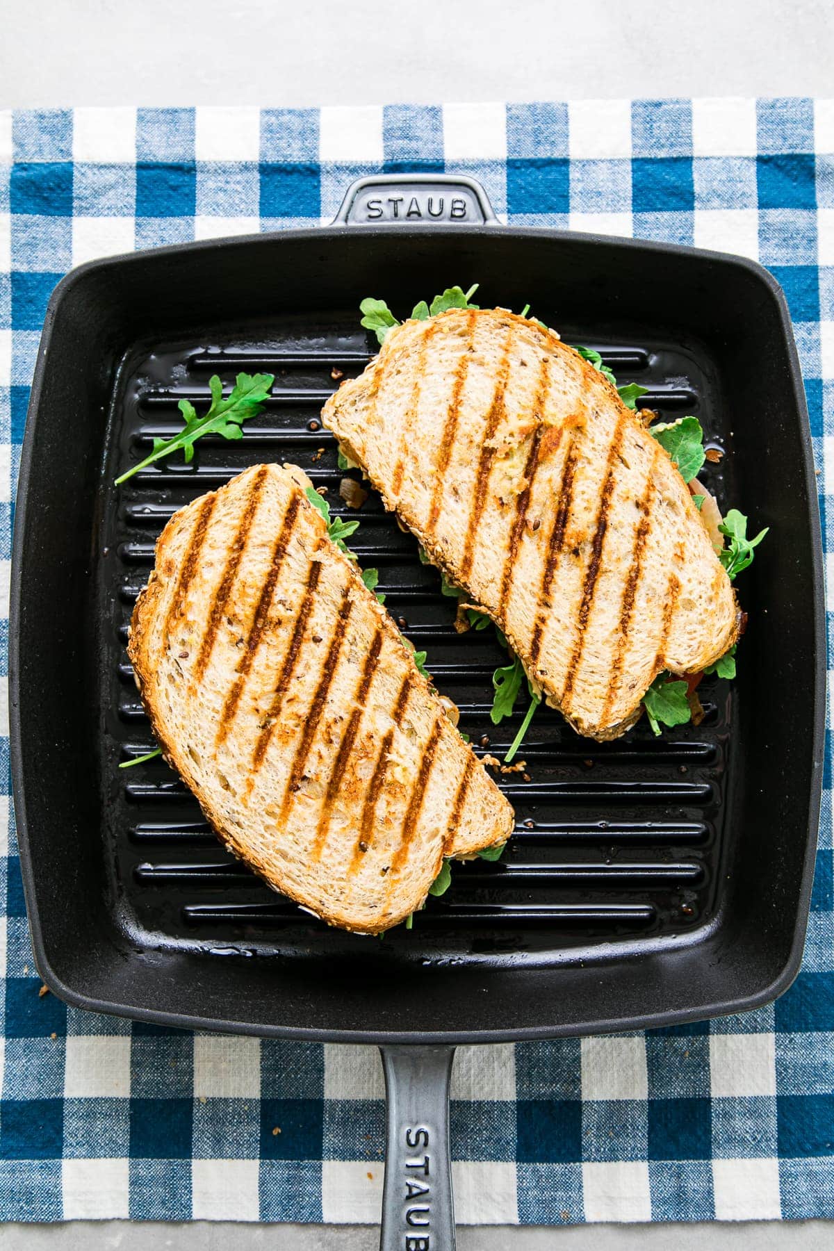top down view of 2 grilled hummus sandwiches cooking on a cast iron griddle.