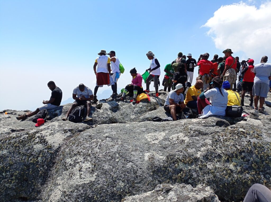 group of hikers sitting and standing on top of large boulder
