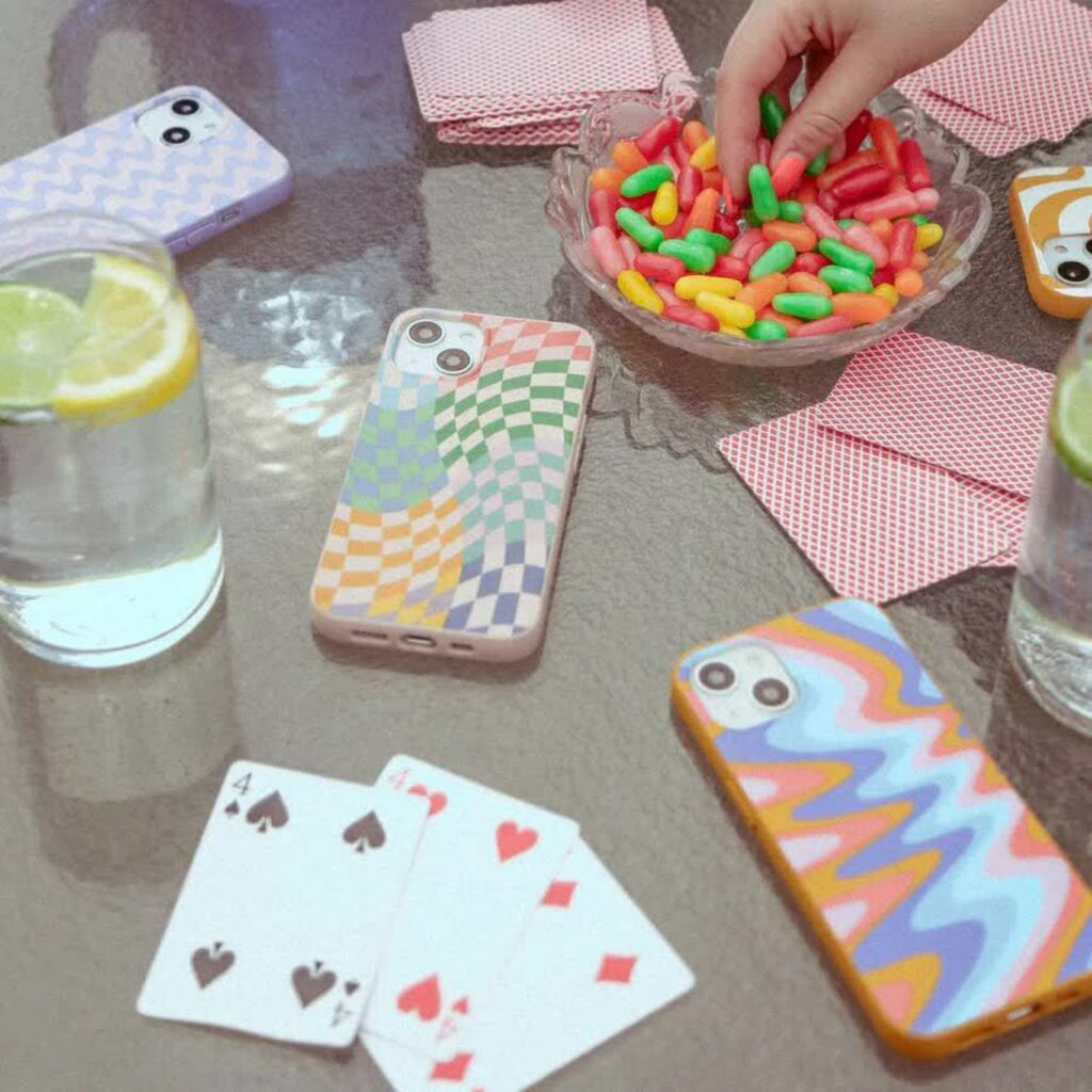 A table strewn with candy, playing cards, and cell phone cases in colorful contemporary designs. 