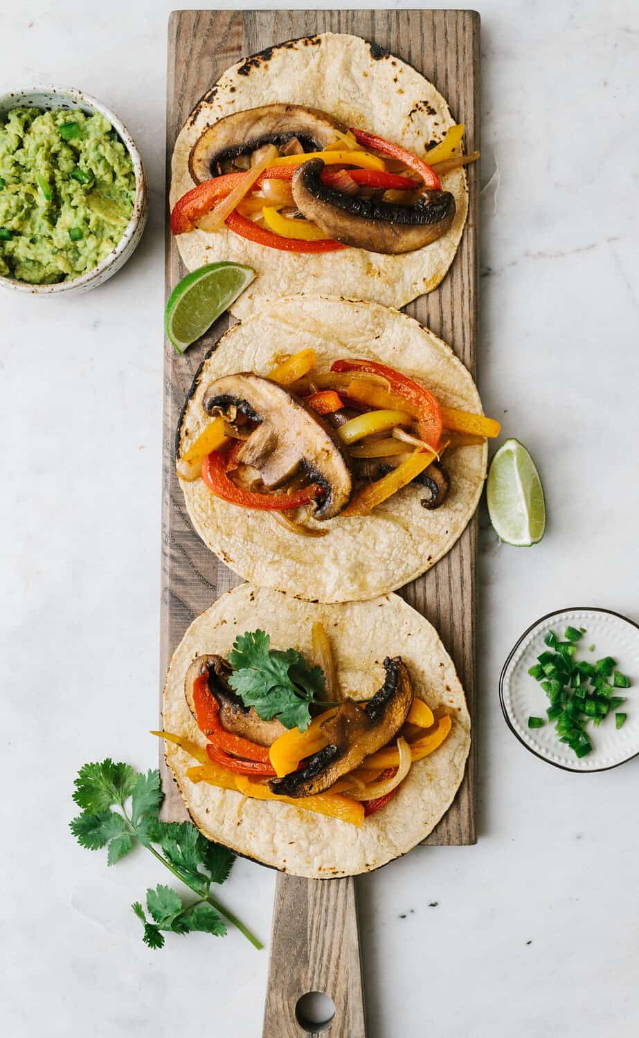 top down view of easy portobello mushroom fajitas on corn tortillas on a wooden serving board.