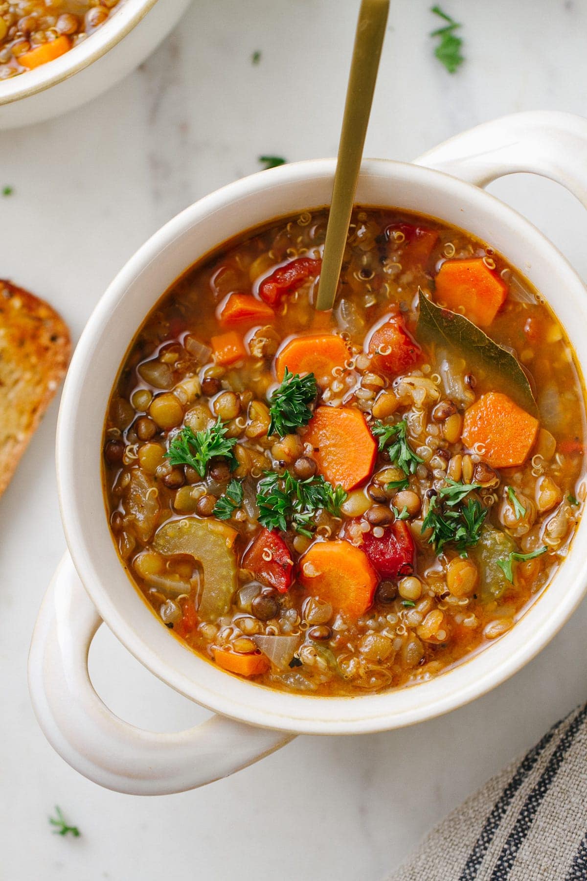 top down view of a bowl with a serving of healthy smoky lentil and quinoa soup with spoon.