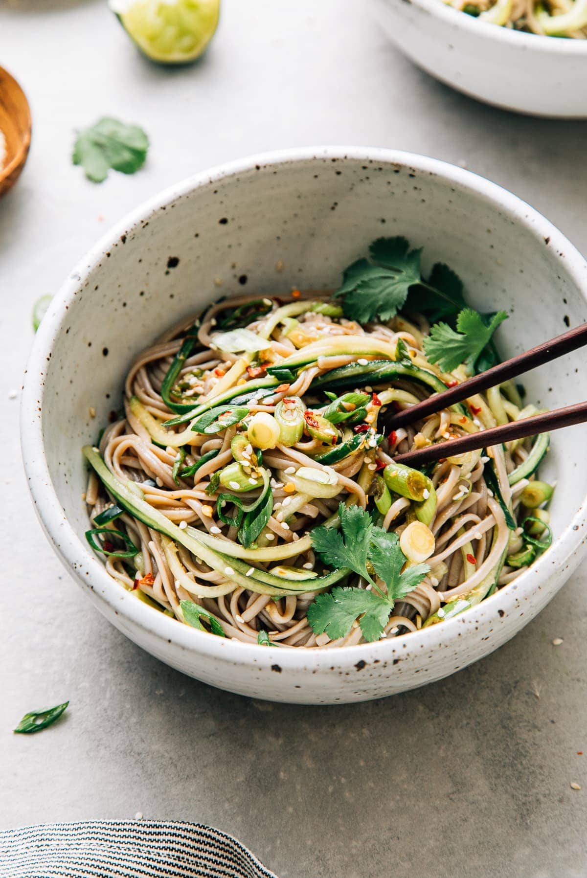 top down view of bowl with serving of soba noodle bowl with cucumber and sesame-ginger scallion sauce with chopsticks.