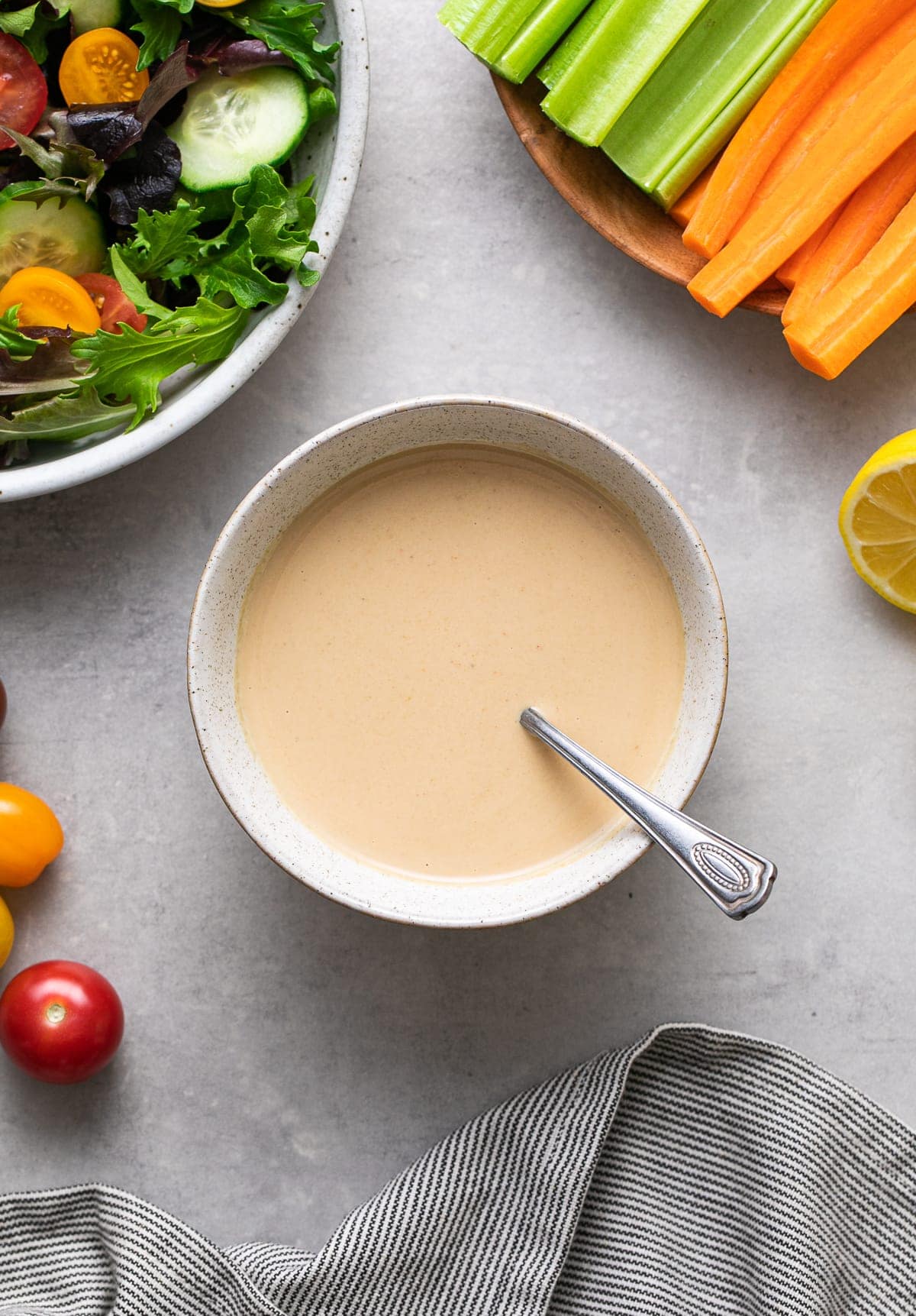 top down view of tahini miso dressing-dip in a bowl with items surrounding.