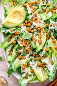 top down view of vegan caesar salad in a large white bowl.