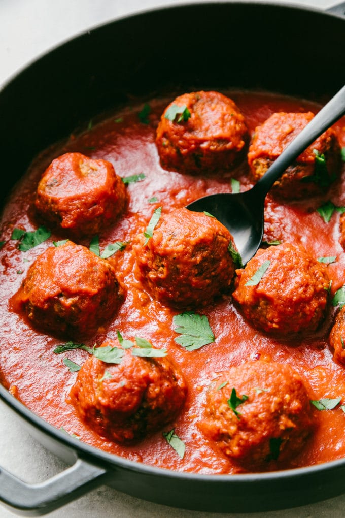 side angle view of pan with vegan meatballs and pasta sauce in a pan.