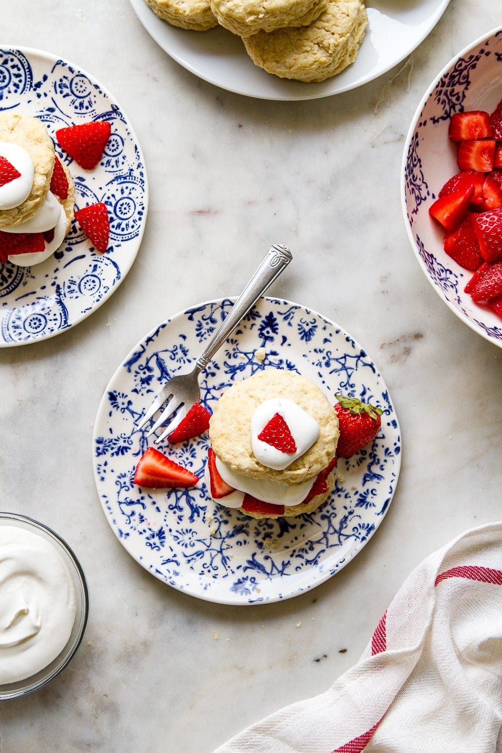 top down view of small plates with vegan strawberry shortcakes surrounded by it's components.